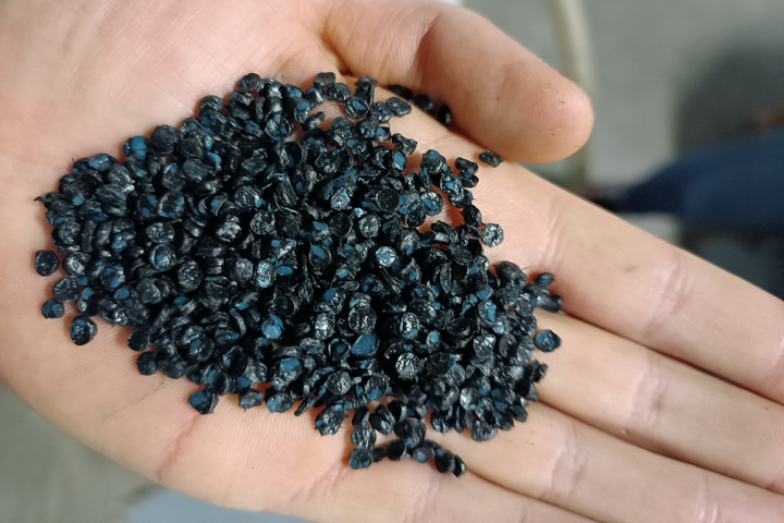 hand holding black recycled plastic pellets